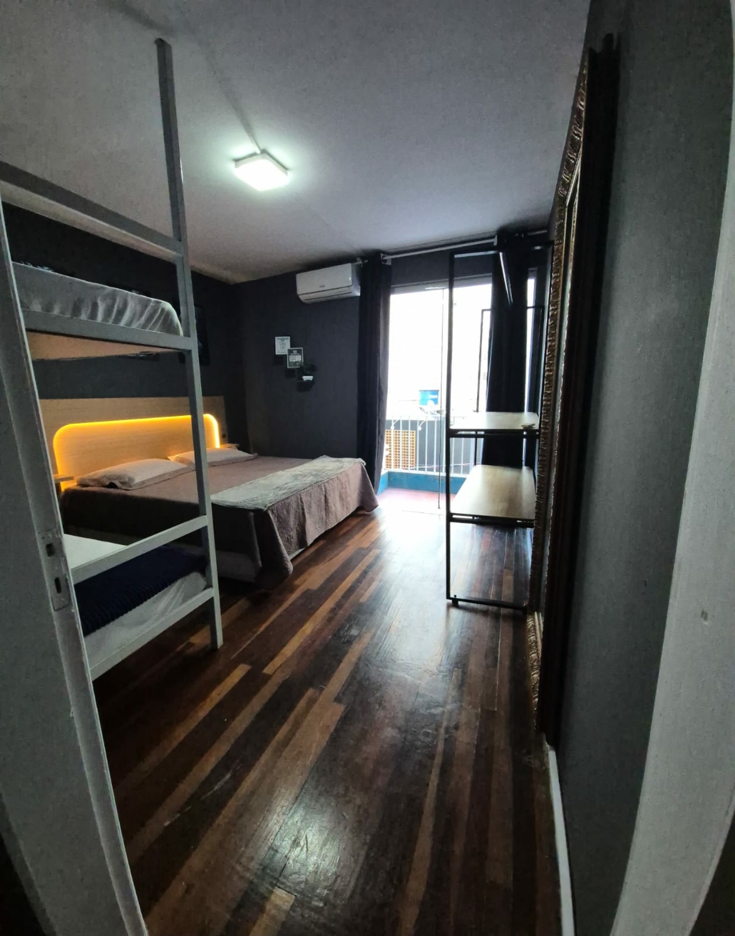 Quarto Zip Rider 11 — Vista interna do quarto com piso de madeira e varanda