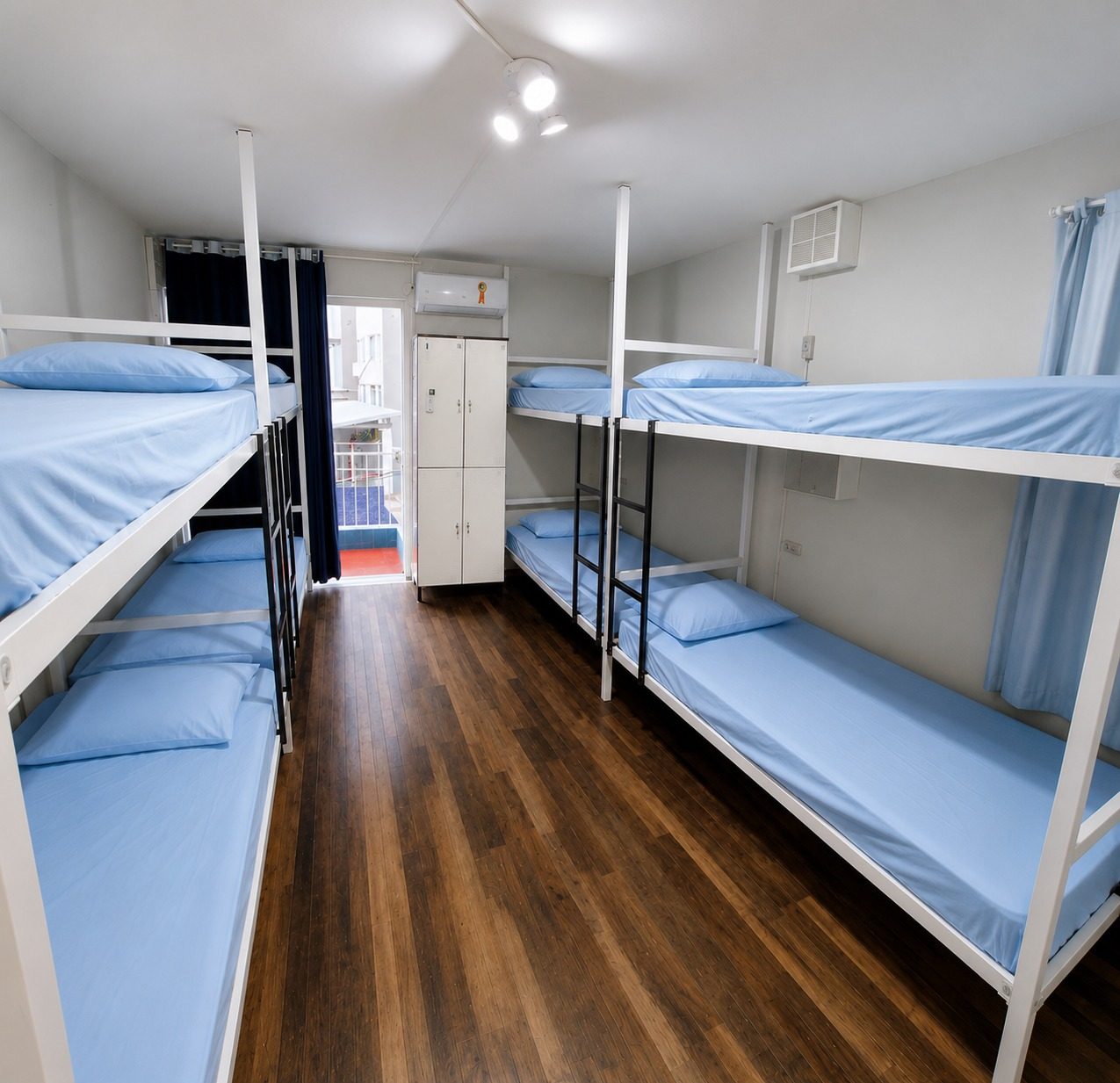Beliches com roupa de cama azul e janela com luz natural