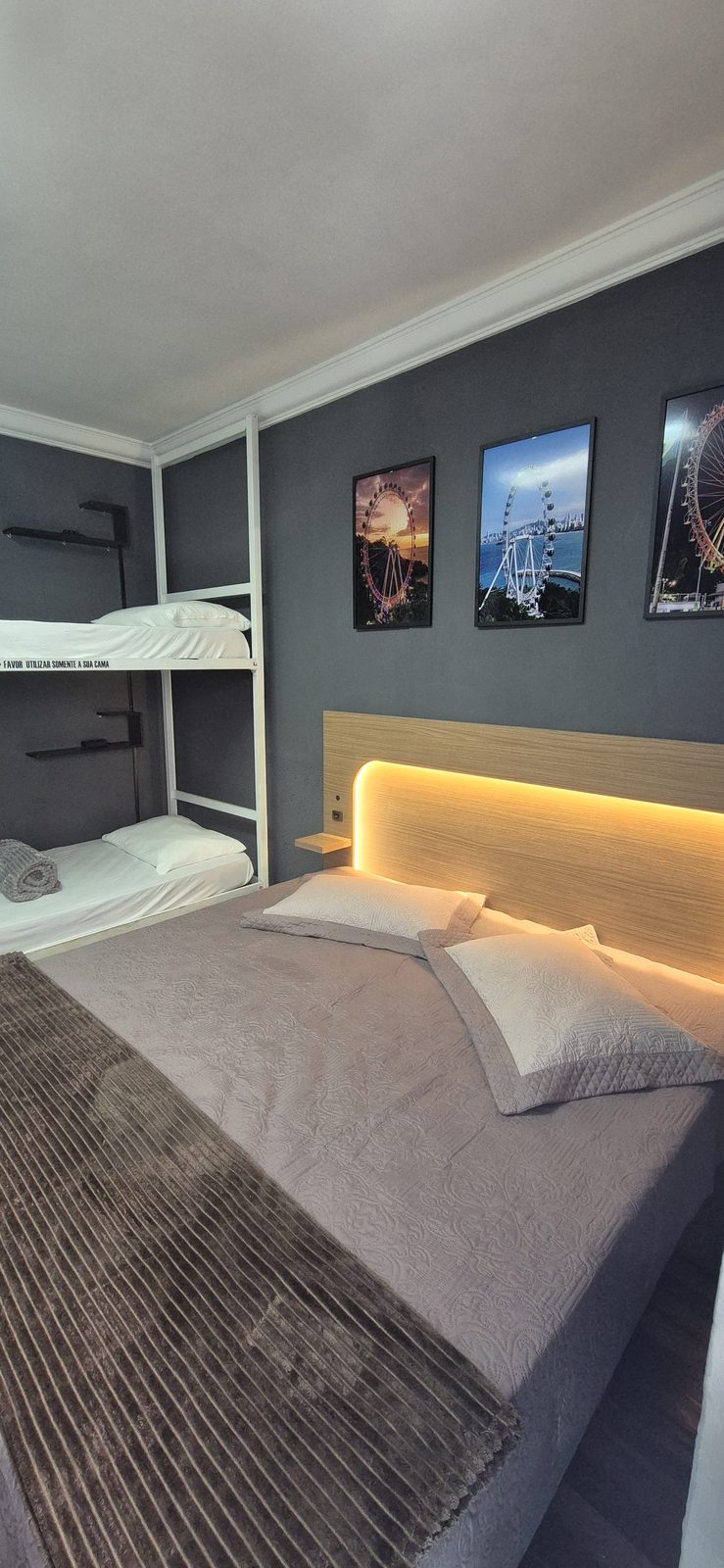 Cama de casal com iluminação de LED na cabeceira e quadros temáticos