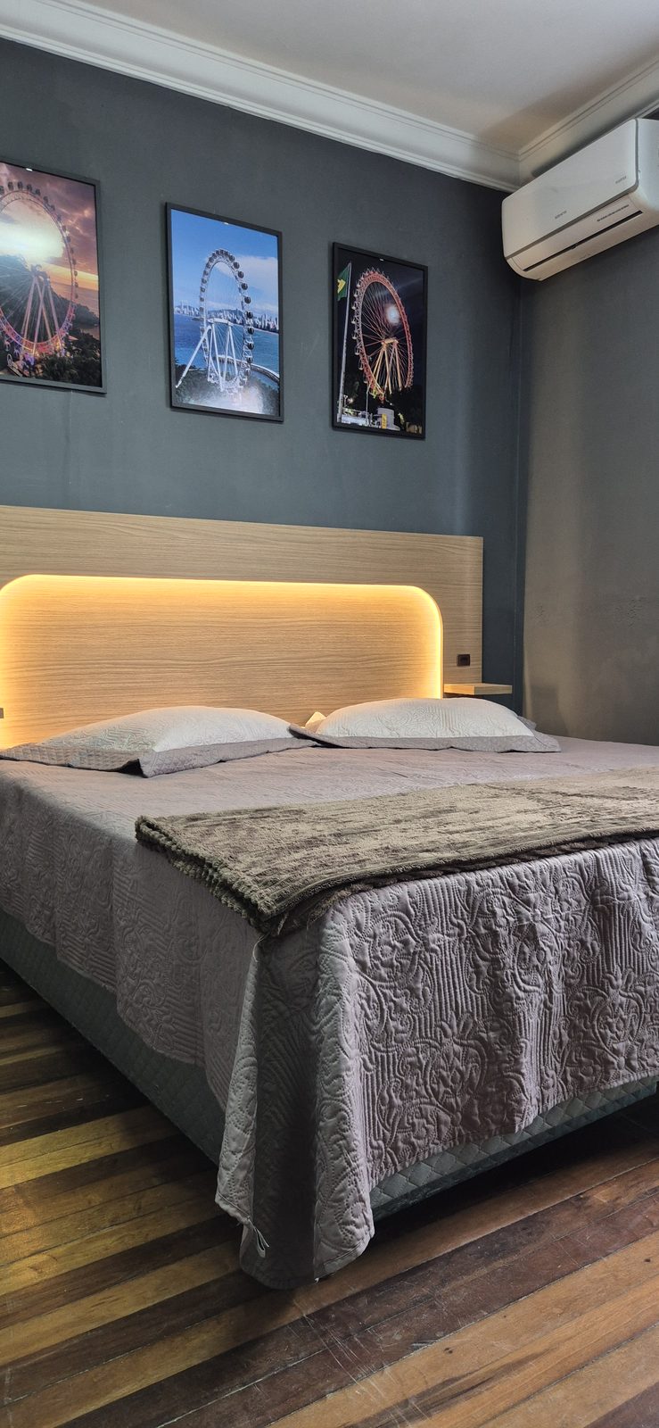 Quarto Big Wheel 04 — Cama de casal vista de frente, com ar-condicionado e quadros na parede
